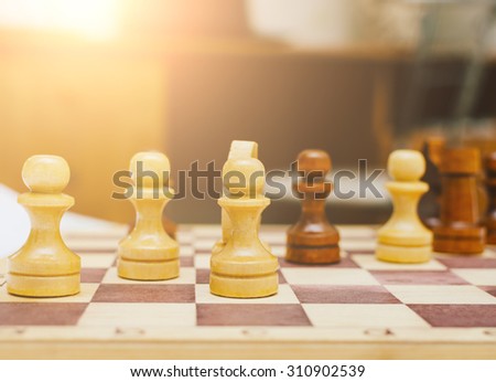 Chess pieces set on a chessboard in the home room or office with beautiful soft sunlight in sunset time