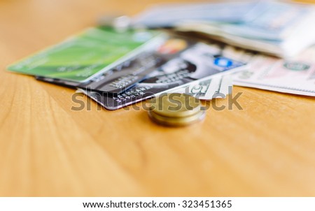 Moneys, credit bank cards and coins on the wood background with sleective focus