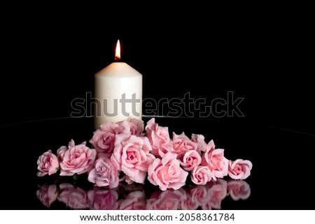 LIGHTED CANDLE AND ELEGANT PINK ROSES ARRANGEMENT ON DARK BACKGROUND. ALL SOULS DAY, DEATH, DECEASE, PRAYER, MEMORIAL DAY, DUEL, MOURNING, GRAVE, CEMETERY, BURIAL AND FUNERAL CONCEPT. Foto d'archivio © 