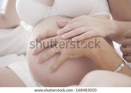 belly pf pregnant woman with father\'s and mother\'s  hends