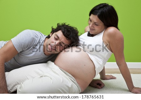Happy father listening to heartbeat of baby in mother\'s tummy