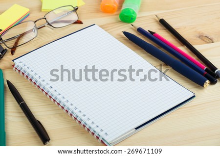 Overhead of open notebook with pen and glasses on a desk
