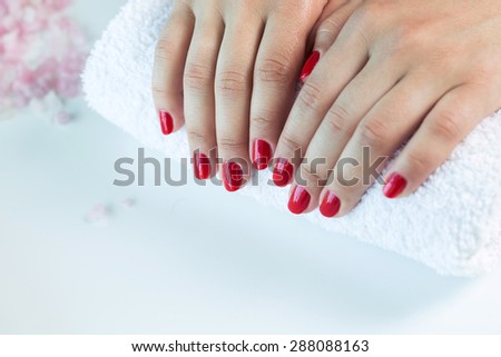 Manicure - Beautiful manicured woman\'s hands with red nail polish on soft white towel