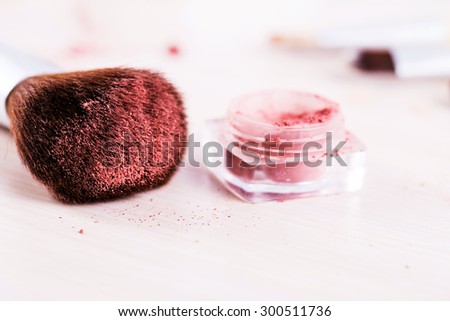 make up brush with red powder . cosmetics