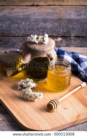 Jar of honey with sunflowers and spoon on old wooden background