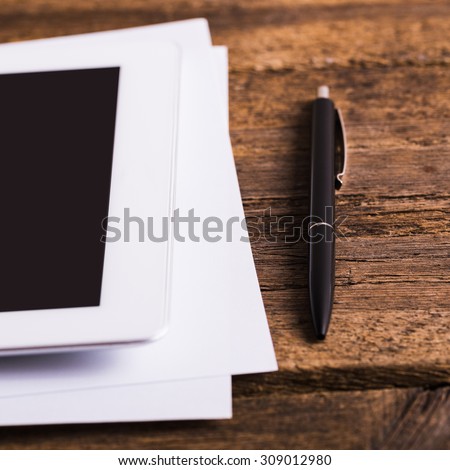 Blank modern digital tablet with papers and pen on a wooden desk. Top view. High quality detailed graphic collage.