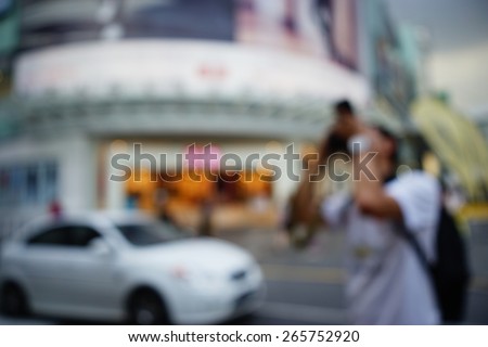 Blurred image of photographer taking a photo in busy crowded night city street with sopping malls. Malaysia. Blur effect and soft focus