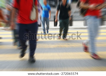 Blurry image of people walking at pedestrian zebra cross during peak hour
