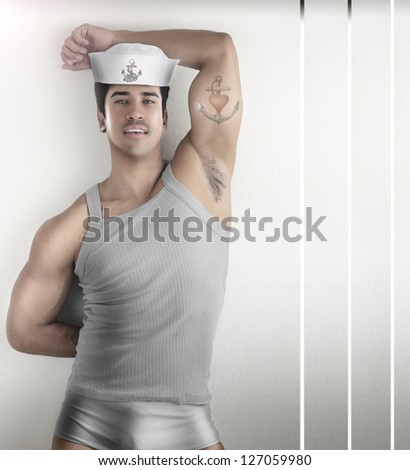 Sexy fashion portrait of a male model in provocative sailor outfit against modern futuristic background