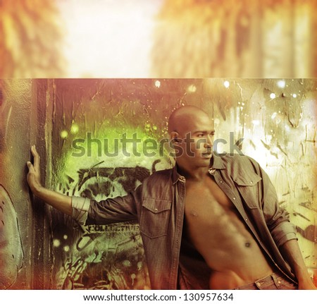 Sexy stylized fashion portrait of male model against urban wall in golden vintage tones