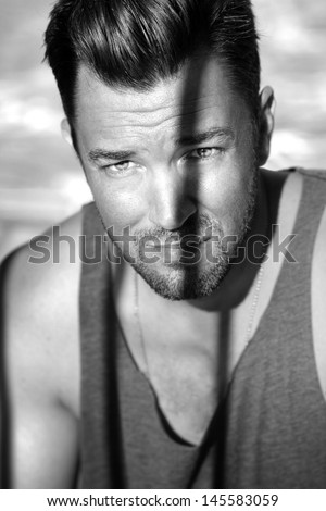 Fine art black and white portrait of a young male model with shadow across face