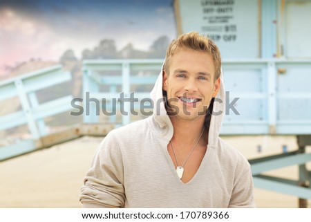 Outdoor portrait of young handsome man with big smile at the beach