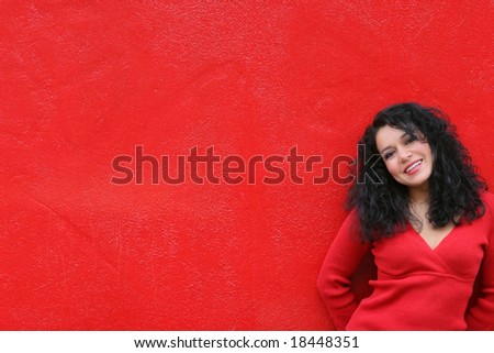 Woman in red smiling wearing red sweater against red wall background