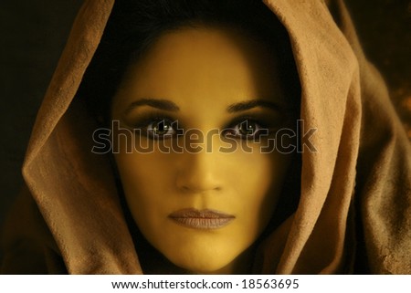 close up of yellow woman\'s face with brown robe wrapped around the head
