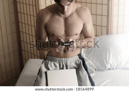young shirtless man on cell phone with a laptop in front of him