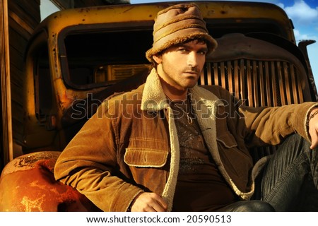 Horizontal portrait of a good looking young male model in brown against a rusty old truck