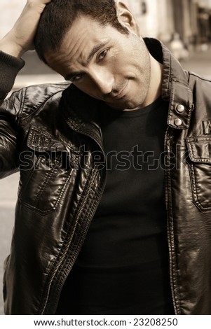 Portrait of a good looking man in classic leather jacket with hand on head