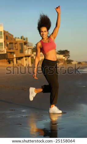 Full body portrait of a happy female fitness model on the beach
