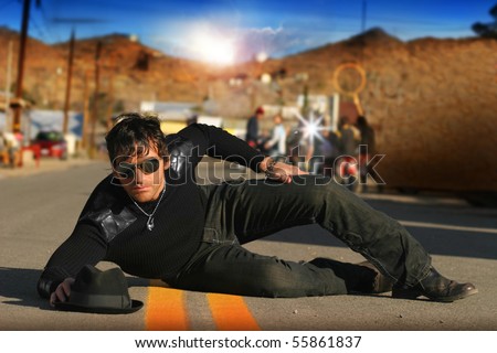 Fashion portrait of trendy male model on set in street with paparazzi behind him