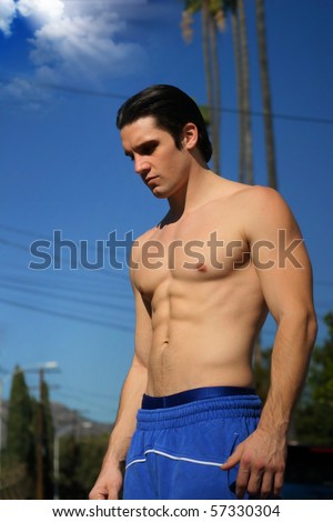 Young muscular male athlete outdoors with blue sky in background