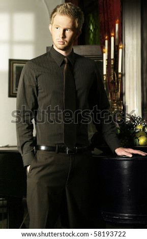 Elegant young man in tie in formal room with window light