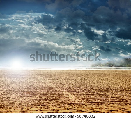 Landscape photo of a beach and dramatic cloud filled sky and sun