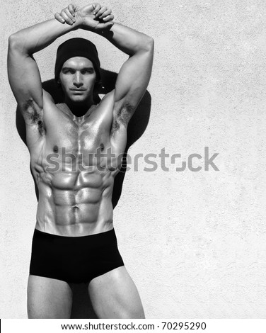 Sexy fine art black and white portrait of a very muscular shirtless male model posing with arms up