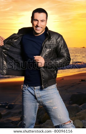 Full body portrait of good looking man in golden light wearing a leather jacket against beautiful sunset