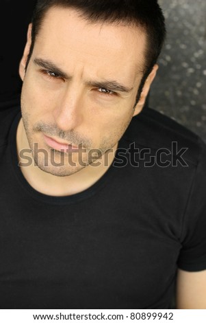 Closeup portrait of a serious man making expression in black shirt