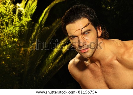 Outdoor portrait of a beautiful young muscular man with long wet hair