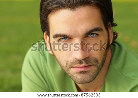 Close up portrait of a good looking male model in green sweater against natural green background