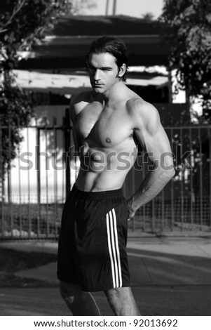 Outdoor black and white portrait of a shirtless good looking fit male model