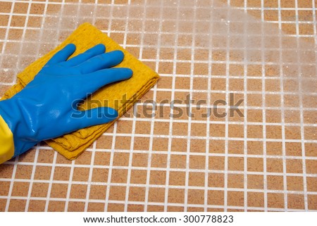 Hand in blue glove with a yellow cloth on brown foam cells