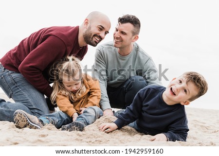 Gay fathers and sons playing on the beach in summer vacation - LGBT family love concept - Main focus on left man face