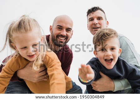 Gay male couple and little sons having fun outdoors during summer vacation - Lgbt and love family concept - Main focus on right father face