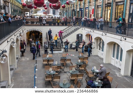 LONDON, UK - NOVEMBER 5, 2014 : Musical string band busking under the lights and Christmas decorations hanging from the roof in the Apple Market at Covent Garden in central London.