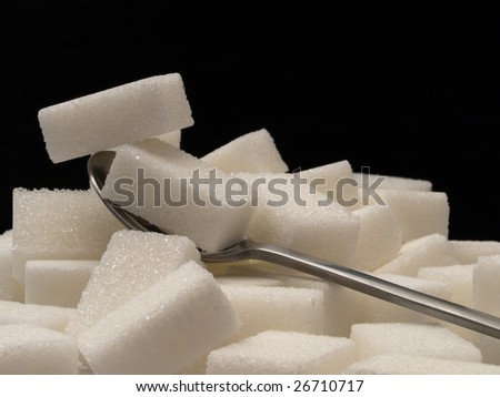 Close-up of white sugar cubes on a dark background with a tea-spoon.