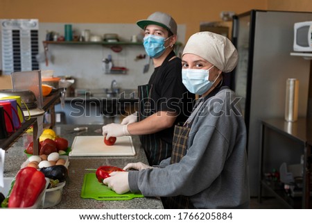 
two young entrepreneurs cooking and handling food with chinstrap and gloves for precaution Foto stock © 