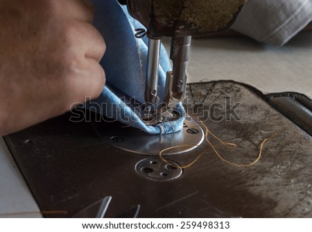 Woman hands sewn fabric repairs on sewing machine in Sewing Process.