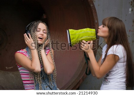 girl singing in megaphone for another girl who listing music in headphones