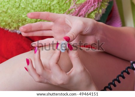 beauty girl paint her nails red enamel on color background