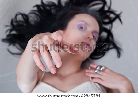 beauty young girl pulls her hand on the gray background