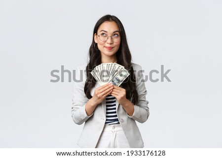 Business, finance and employment, entrepreneur and money concept. Dreamy pleased businesswoman thinking where go vacation and how invest earned dollars, hold cash and looking up thoughtful Foto stock © 