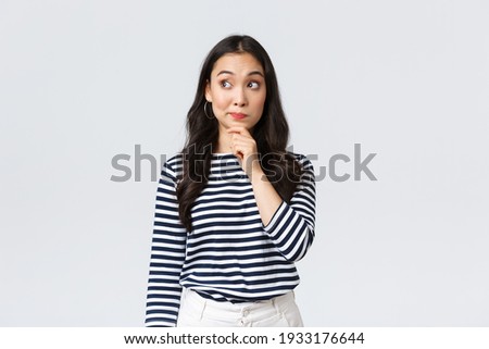 Lifestyle, beauty and fashion, people emotions concept. Thoughtful young asian girl searching for solution, thinking looking away and touching chin while pondering decision