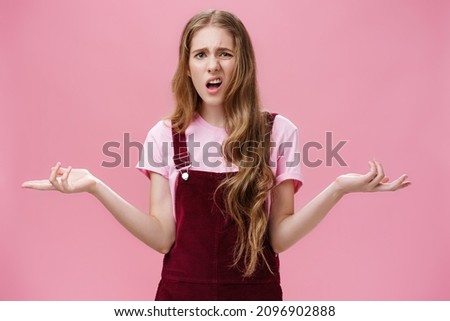 So what, no big deal. Rude and impolite arrogant young girl with high ego in overalls spreading hands sideways in questioned, bothered gesture expressing confusion, feeling pissed with stupid question Foto stock © 
