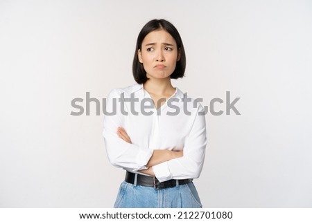 Photo of Image of sad office girl, asian woman sulking and frowning disappointed, standing upset and distressed against white background