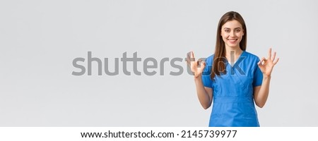 Healthcare workers, prevent virus, insurance and medicine concept. Confident young female nurse, doctor in blue scrubs assure quality of test results in their clinic lub, show okay sign, guarantee Zdjęcia stock © 