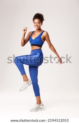 Similar – Image, Stock Photo Beautiful girl athlete, african tanned skin. Smiles to camera while Warms up muscles before doing urban yoga training.Leg joints articular gymnastics. Music while training. Sitting floor copy space