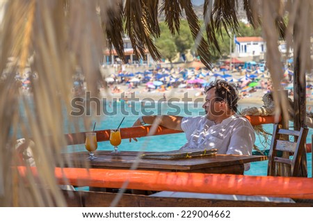 Man has a rest in Akuna Matata bar an drinks orange juice at Matala beach, Crete island, Greece