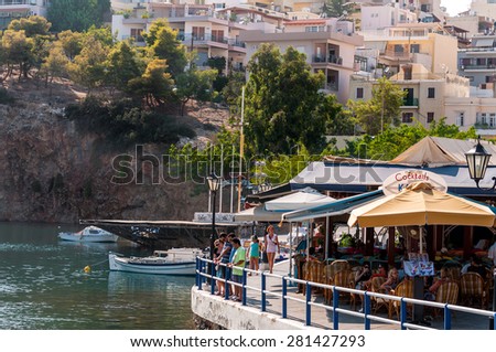 AGHIOS NIKOLAOS - AUGUST 2013: Cafe with tourists near lake at port of Aghios Nikolaos on Crete island, Greece.